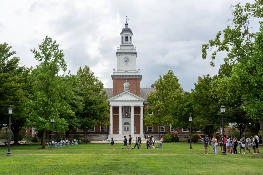 students walk past Gilman Hall on the Johns Hopkins University campus