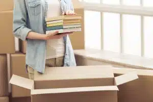 An unidentified girl holding a pile of books.