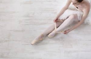 a ballet student fixing her ballet shoes