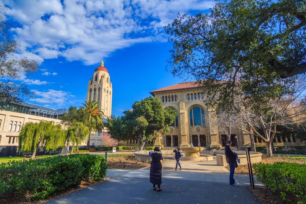 Stanford University's bell tower and academic building with some students walking in front