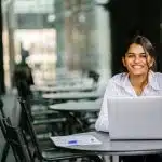 a female intern looking at the camera while she is in front of her laptop