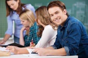 Young man smiling at the camera while in a classroom.