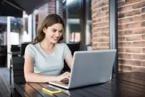 Young woman using a laptop in front of a person.