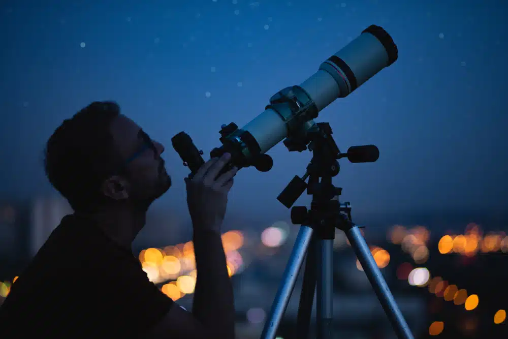 a male astronomer looking through his telescope