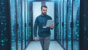 a male computer science professional walking in between huge machines