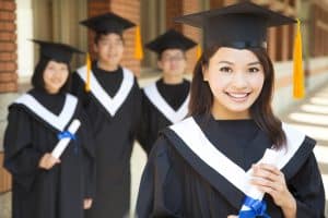 Asian students wearing a graduation gown and looking at the camera