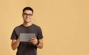 a male student holding a tablet and looking at the camera