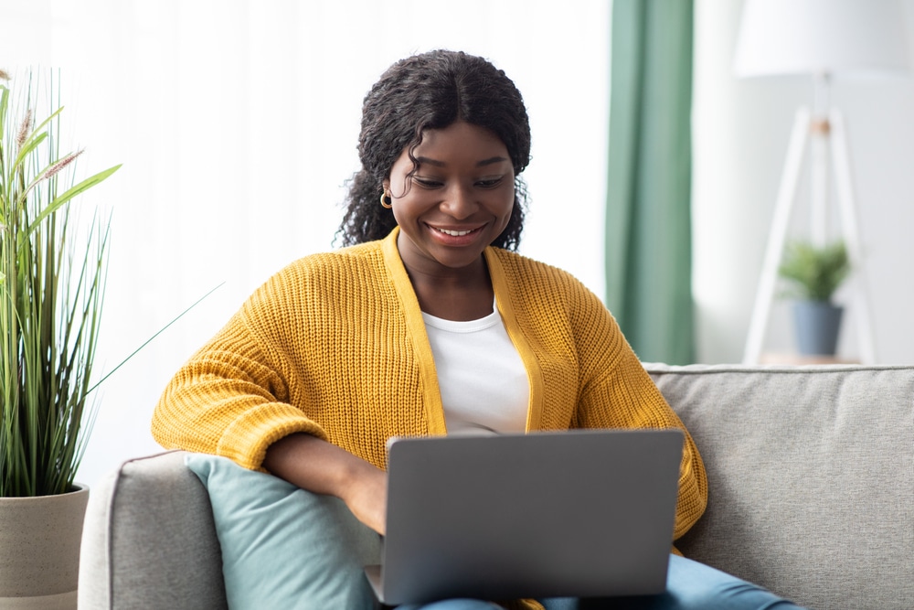 Young woman using a laptop while sitting on a couch.