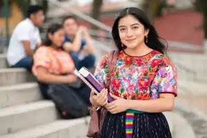 a female student looking at the camera while holding her school text books