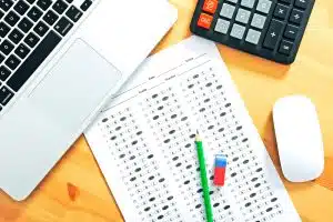 an answer sheet, a laptop and a calculator sprawled on a table