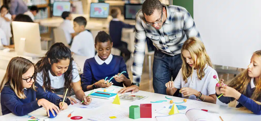 students inside a class being supervised by a male teacher