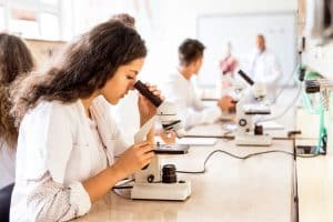 Female student looking into a microscope in a laboratory.