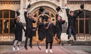 college students taking a jump shot while wearing their graduation gowns