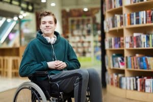 Young man sitting on a wheelchair while smiling at the camera.