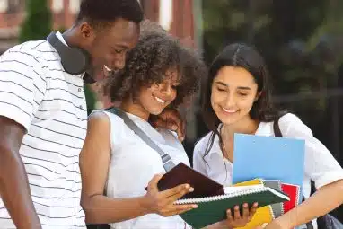 University students checking something in a notebook.