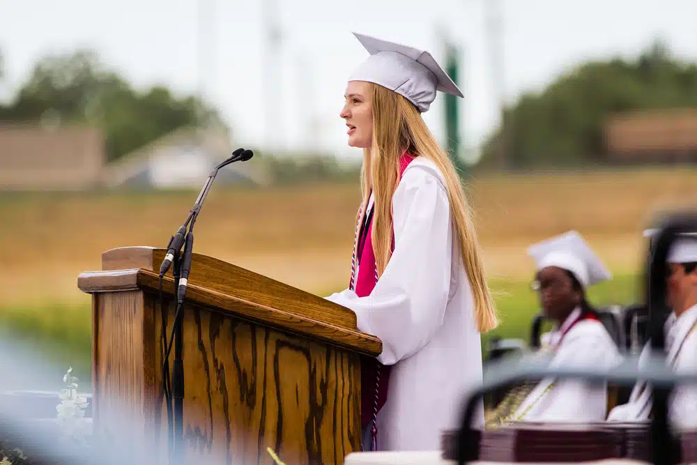 Female high school valedictorian giving a speech.