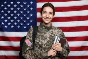 Female Cadet With Backpack And Books Against American Flag