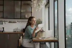 Happy young woman reading paper letter at home.