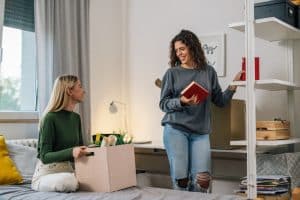 Two students keeping their dorm room clean.