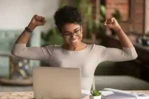 View of a woman looking excited while looking at her laptop.