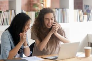 Two students looking excited while staring at their computer