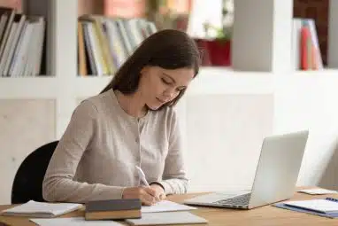 View of a woman writing in a table.