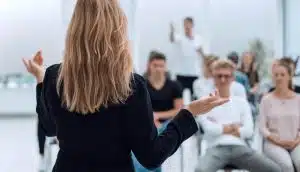 Background of a woman talking to a set of students.