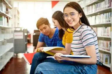 Three college students study together in a library, representing Case Western vs UIUC.