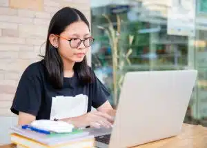 Junior high school girl doing homework at home with laptop.