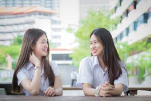 Two young Asian girls students are consulting together