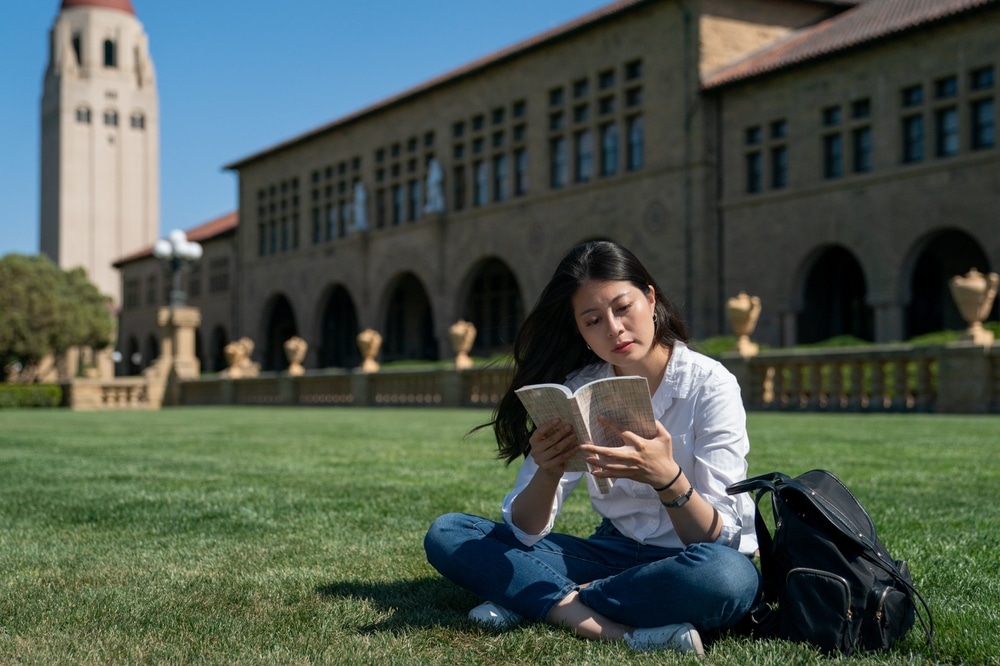 a female student sitting on a field waiting for the campus tour to commence