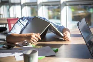 a tired employee putting his laptop above his head