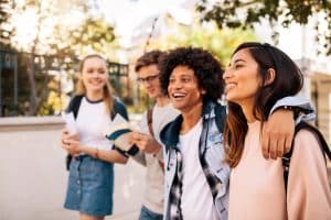 College students walking together outdoors. Group of young people in college campus.