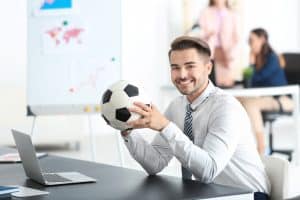 Young handsome man with soccer ball in office