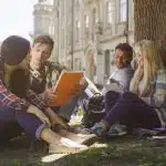 A group of college students sit under a tree studying together, representing the choice between UPenn vs Columbia.