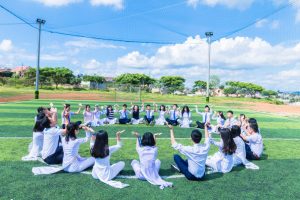students having an activity, sitting on a grass field in campus