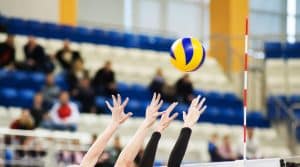 Volleyball players ' hands are above the volleyball net