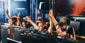 Team of happy proffesional cyber sport gamers giving high five to each other while participating in eSports tournament