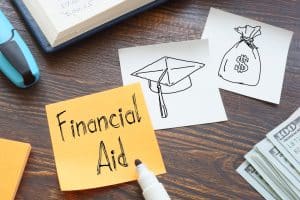 A post it note with the word Financial aid placed next to a drawing of a graduation hat.