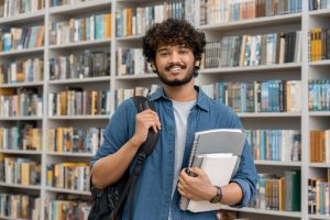 A young man inside the library smiling at the camera