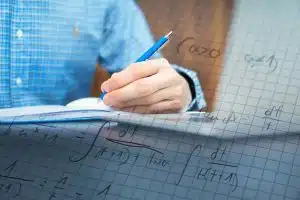 man is studying for his exam, solving math problems to practice.