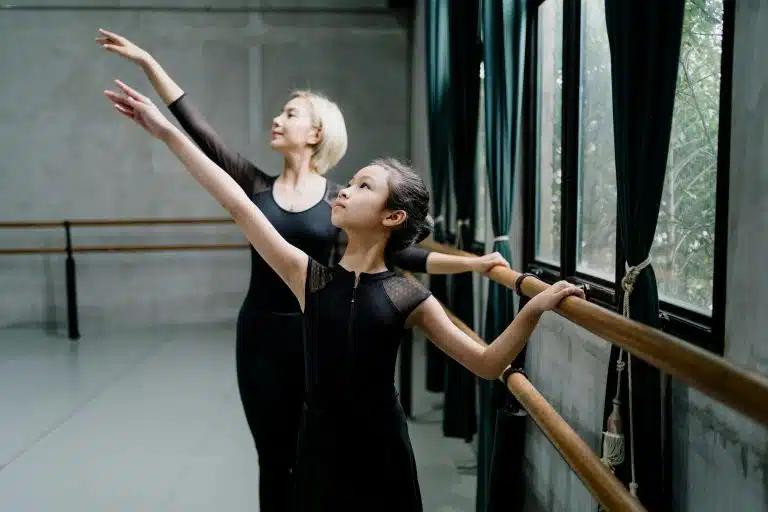 Ballet teacher teaching her student to dance in a studio