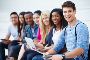 University students sitting next to each other next to a building.