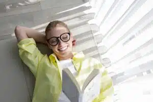 Young beautiful woman wearing yellow shirt reading a book at home.