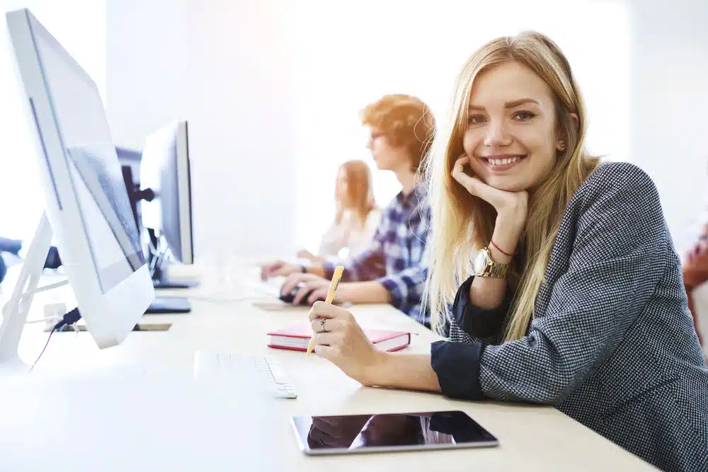Young woman smiling at the camera while in front of the computer.