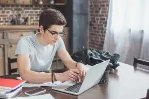 Male student typing in his laptop.