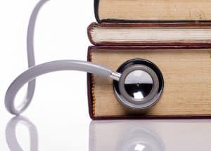 A pile of books and a stethoscope placed next to each other.