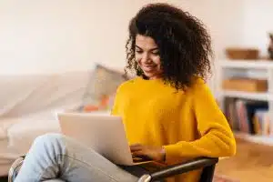 View of a student using her laptop while writing.