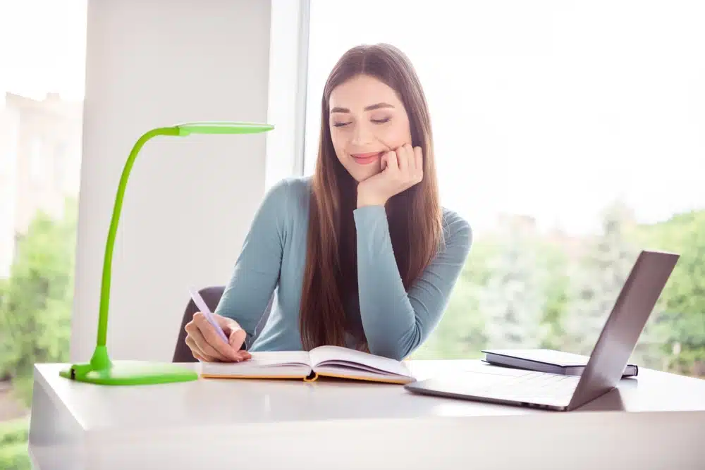 Female student smiling while writing.