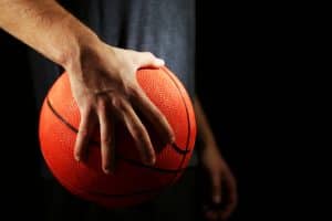 Holding a basketball with one hand.